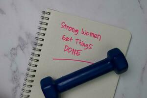 Strong Women Get Things Done write on a book isolated wooden table. photo