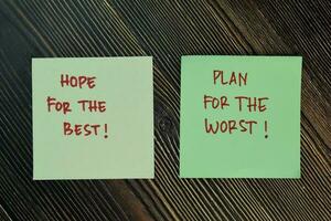 Hope For The Best and Plan For The Worst write on sticky notes isolated on Wooden Table. photo