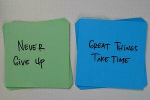 Never Give Up - Great Things Take Time write on sticky notes isolated on Wooden Table. photo