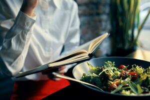 woman with notepad near the window and salad in a plate tomatoes fresh vegetables photo