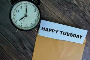 Happy Tuesday text on document above brown envelope. photo