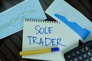 Sole Trader write on a book isolated on Wooden Table. photo