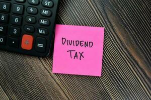 Concept of Dividend Tax write on sticky notes isolated on Wooden Table. photo