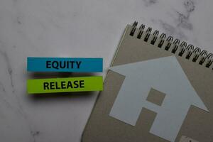 Equity Release write on sticky note and house made from paper isolated on Office Desk. Retirement concept photo