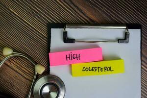 High Colesterol write on sticky notes isolated on Wooden Table. photo