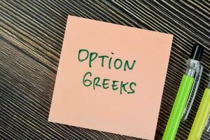 Concept of Option Greeks write on sticky notes isolated on Wooden Table. photo