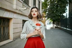 bonito mujer rojo falda café taza al aire libre caminar foto