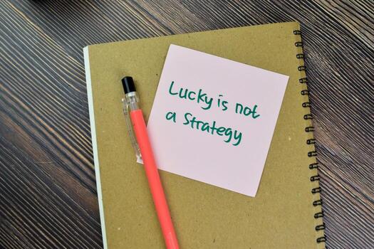 Concept of Lucky is Not a Strategy write on sticky notes isolated on Wooden Table. photo