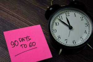 90 Days To Go write on sticky note isolated on wooden table. photo