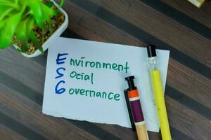 Concept of ESG - Environment Social Governance write on sticky notes isolated on Wooden Table. photo