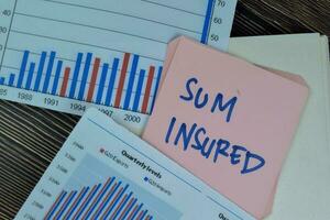 Concept of Sum Insured write on sticky notes isolated on Wooden Table. photo