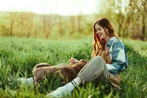 mujer felizmente sonriente a jugando con su pequeño perro al aire libre en Fresco verde césped en el verano Brillo Solar su y su perros salud, salud concepto y oportuno tratamiento para insectos garrapatas y garrapata pulgas foto