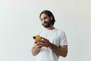 Man blogger holds a phone in his hands and communicates with people online in social networks with a smile and a white t-shirt on a white background photo