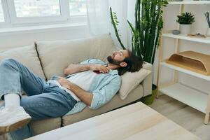 A man sleeping on the couch during the day is tired and relaxed after stress and feeling bad. Stress at work, poor sleep and health problems photo