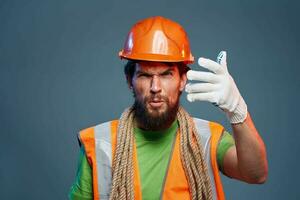 Man in orange paint glove professional construction blue background photo