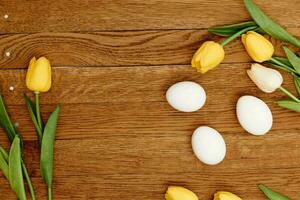 white chicken eggs yellow tulips spring holiday wooden background photo