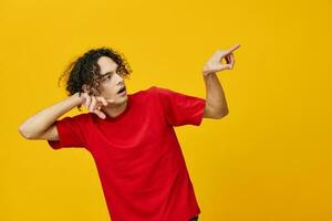 confuso gracioso caucásico joven hombre en rojo camiseta punto ambos manos aparte posando aislado en terminado amarillo estudio antecedentes. el mejor oferta con gratis sitio para publicidad. emociones para todos los días concepto foto