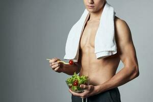 sporty man pumped up torso towel on shoulders plate of salad vegetarian cropped view photo