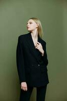 An attractive cool professional model holds a jacket by the lapel collar and poses on a green olive background in the studio. Cool banner for brands photo