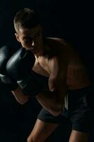 boxer in gloves on a black background bent down photo