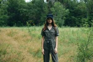 woman in nature in a gray overalls and a cap on her head photo