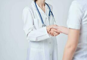 Doctor and patient shake hands with each other on a light background cropped view photo