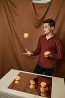 A man in a red shirt elegant style and oranges in the hands of a table with a mirror photo