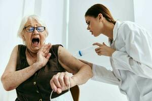 enfermero inyectando un mayor mujer con un grande jeringuilla inmunidad proteccion foto
