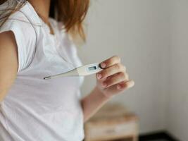 woman with armpit thermometer checking temperature photo