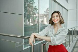 alegre rubia cerca el edificio posando Moda rojo falda foto