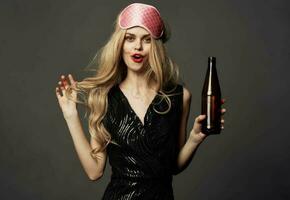 Beautiful blonde with a pink sleep mask and a bottle of beer in her hand photo