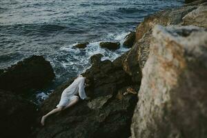 Barefoot woman lying on her back on a rocky seashore unaltered photo