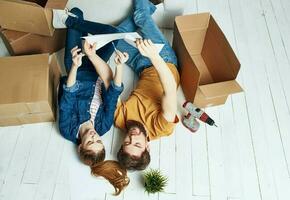 man and woman indoors with boxes on the floor moving fun flower in a pot photo