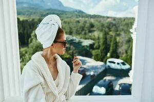 beautiful woman wearing sunglasses posing in a bathrobe on a balcony rest Lifestyle photo