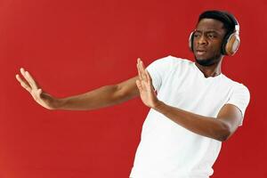 African man in white T-shirt wearing headphones gestures with his hands emotions photo