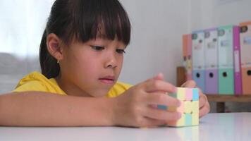 ásia pequeno fofa menina segurando rubik's cubo dentro dela mãos e jogando com isto. rubik's cubo é uma jogos este aumenta inteligência para crianças. video