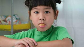 gelukkig schattig weinig meisje aan het eten gelatine snoep. grappig kind met kauwen gom. mooi weinig meisje met met vitamines voor kinderen Leuk vinden gelei snoep. video