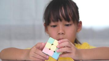 asiatico poco carino ragazza Tenere di rubik cubo nel sua mani e giocando con esso. di rubik cubo è un' gioco quello aumenta intelligenza per bambini. video