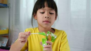 schattig weinig meisje aan het eten lolly. grappig kind met lolly snoep. kind aan het eten snoepgoed. video