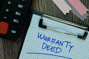 Warranty Deed write on a paperwork isolated on Wooden Table. Business or Financial Concept photo