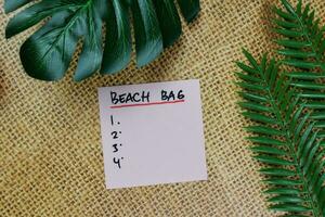 Beach Bag write on sticky notes and supported by additional services isolated on Wooden Table. photo