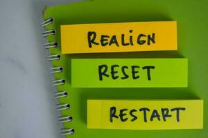 Realign, Reset, Restart write on sticky notes isolated on Wooden Table. photo