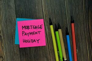 Mortgage Payment Holiday write on sticky note isolated on wooden table. photo