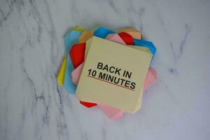 Back in 10 Minutes write on sticky notes isolated on Wooden Table. photo