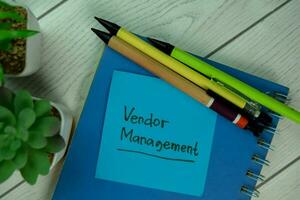 Vendor Management write on sticky notes isolated on Wooden Table. photo