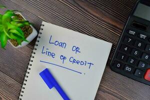 Loan or Line of Credit write on a book isolated on Wooden Table. photo