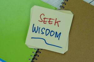 Concept of Seek Wisdom write on sticky notes isolated on Wooden Table. photo