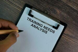 Training Needs Analysis write on a paperwork isolated on Wooden Table. photo