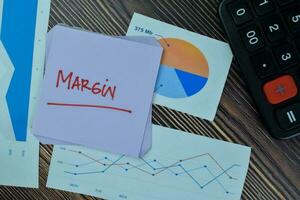 Concept of Margin write on sticky notes isolated on Wooden Table. photo