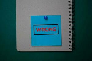 Wrong write on a sticky note isolated on green background. photo